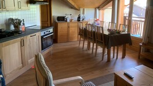 Interior de fusta amb cuina, zona de menjador i vista per una porta corredissa.