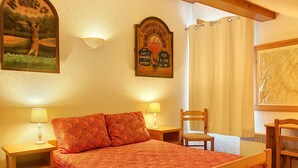 Un dormitori amb un llit de fusta, dues taules de nit amb làmpades, una cadira, i una paret amb un quadre amb marc i un senyal.