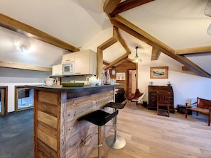 A rustic kitchen with wooden beams, a bar area with stools, and a dining table with chairs. - Spacious apartment 6 pers. · Near slopes · Balcony · WIFI (Saint-Martin-de-Belleville-Les Menuires)