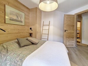 A bedroom with a bed, pillows, a ladder, a door, and a framed picture on the wall. - Spacious apartment 6 pers. · Near slopes · Balcony · WIFI (Saint-Martin-de-Belleville-Les Menuires)