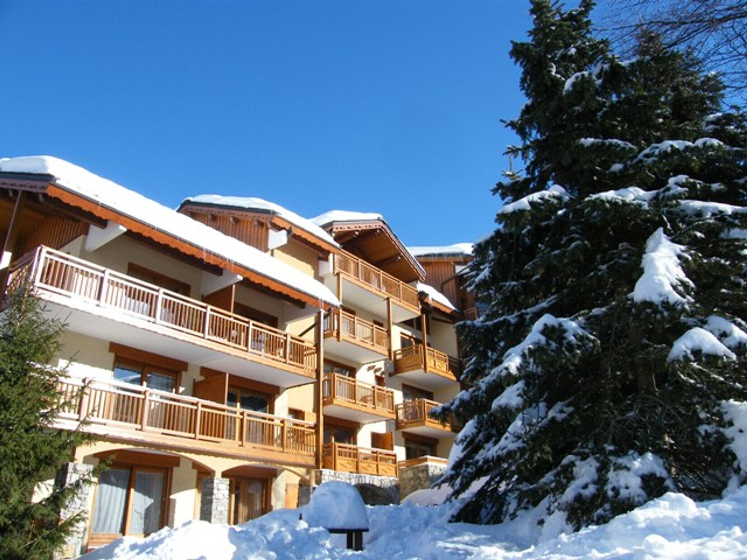 A multi-story hotel with balconies, surrounded by snow-covered trees.