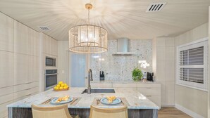 Una cocina moderna con una isla central, electrodomésticos de acero inoxidable y un diseño de techo original.
