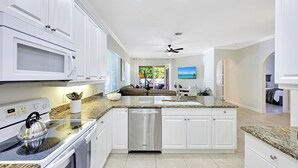 A modern kitchen with white cabinetry, granite countertops, a stainless steel dishwasher, and a built-in oven. - Dolphin Dreams | Private Pool | Naples Park Retreat (Naples)