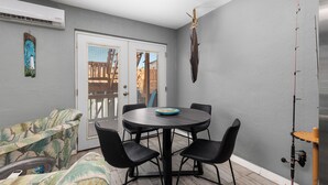 A compact living space with a round dining table, four black chairs, a hammock, and a fishing rod.