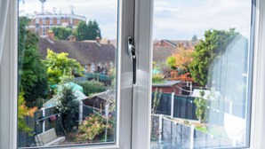 Ein Fenster mit Blick auf ein Wohngebiet, inklusive Häuser und Grünflächen.