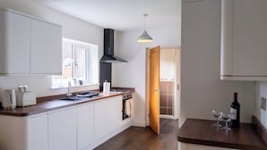 Eine moderne Küche mit weißen Schränken, einer Holz Arbeitsplatte, einem eingebauten Backofen und einer schwarzen Dunstabzugshaube.