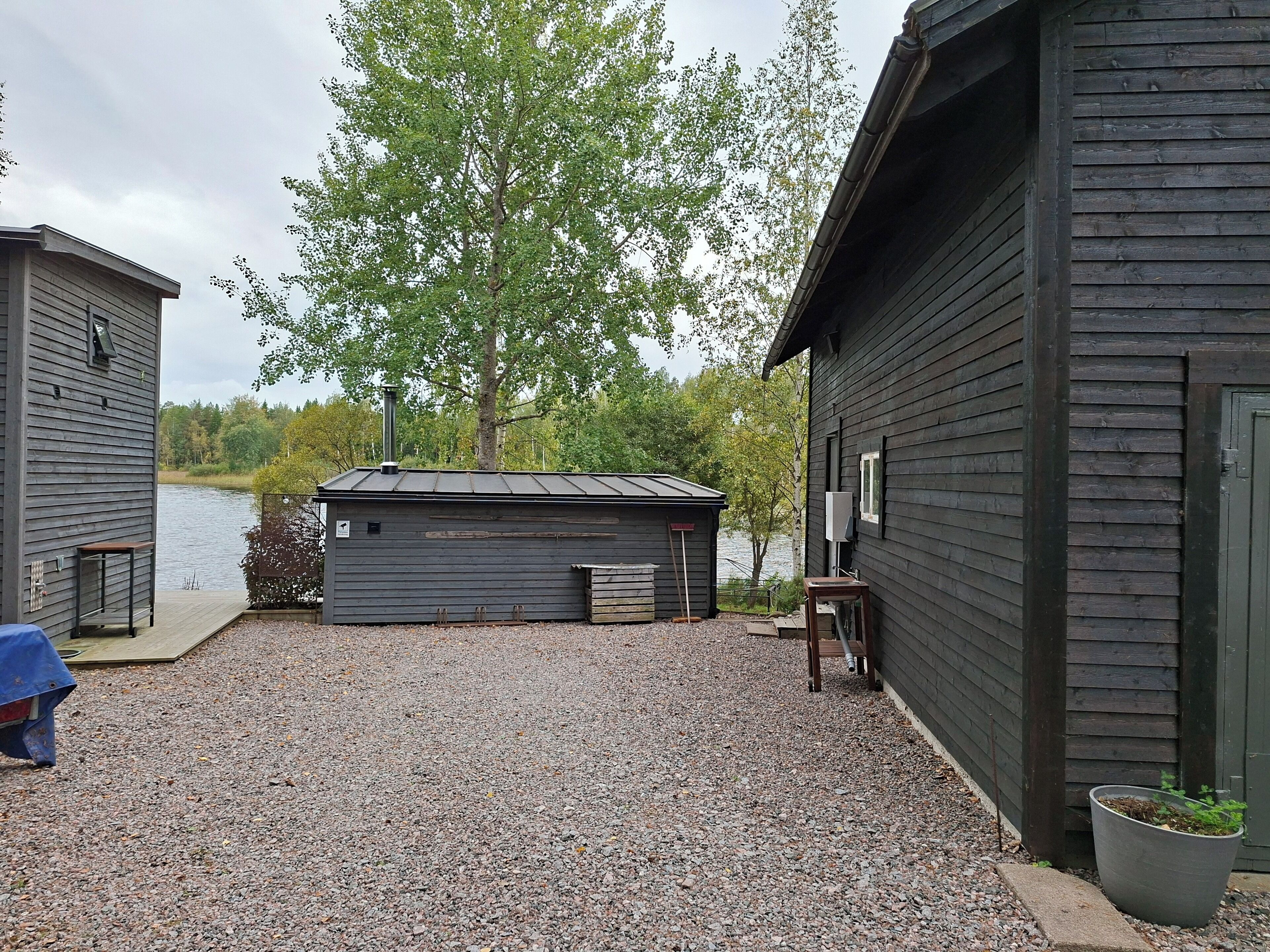 A gravel driveway leading to a cabin with a dock extending into a lake.