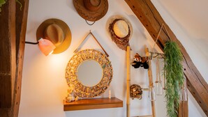 A rustic interior with wooden beams, a wall-mounted mirror, and decorative hats. - Rooms at the Gates of Chambord – Breakfast Included and Table d'Hôtes Available (Vineuil)