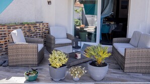 A patio with wicker furniture, potted plants, and a sliding glass door leading to an indoor area. - Rooms at the Gates of Chambord – Breakfast Included and Table d'Hôtes Available (Vineuil)