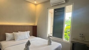 Une chambre d’hôtel avec un lit, un bureau et une fenêtre donnant sur un paysage verdoyant.