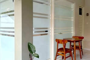 A room with a glass partition, a wooden chair, and a potted plant. - El Nipa Hotel Labuan Bajo (Wae Kelambu)