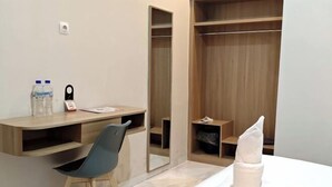Une chambre d’hôtel équipée d’un bureau, d’une chaise, d’un lit et d’une armoire en bois.