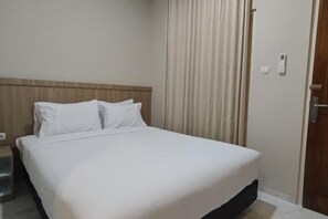 A hotel room with a bed, a nightstand, a door, and a curtain. - El Nipa Hotel Labuan Bajo (Wae Kelambu)