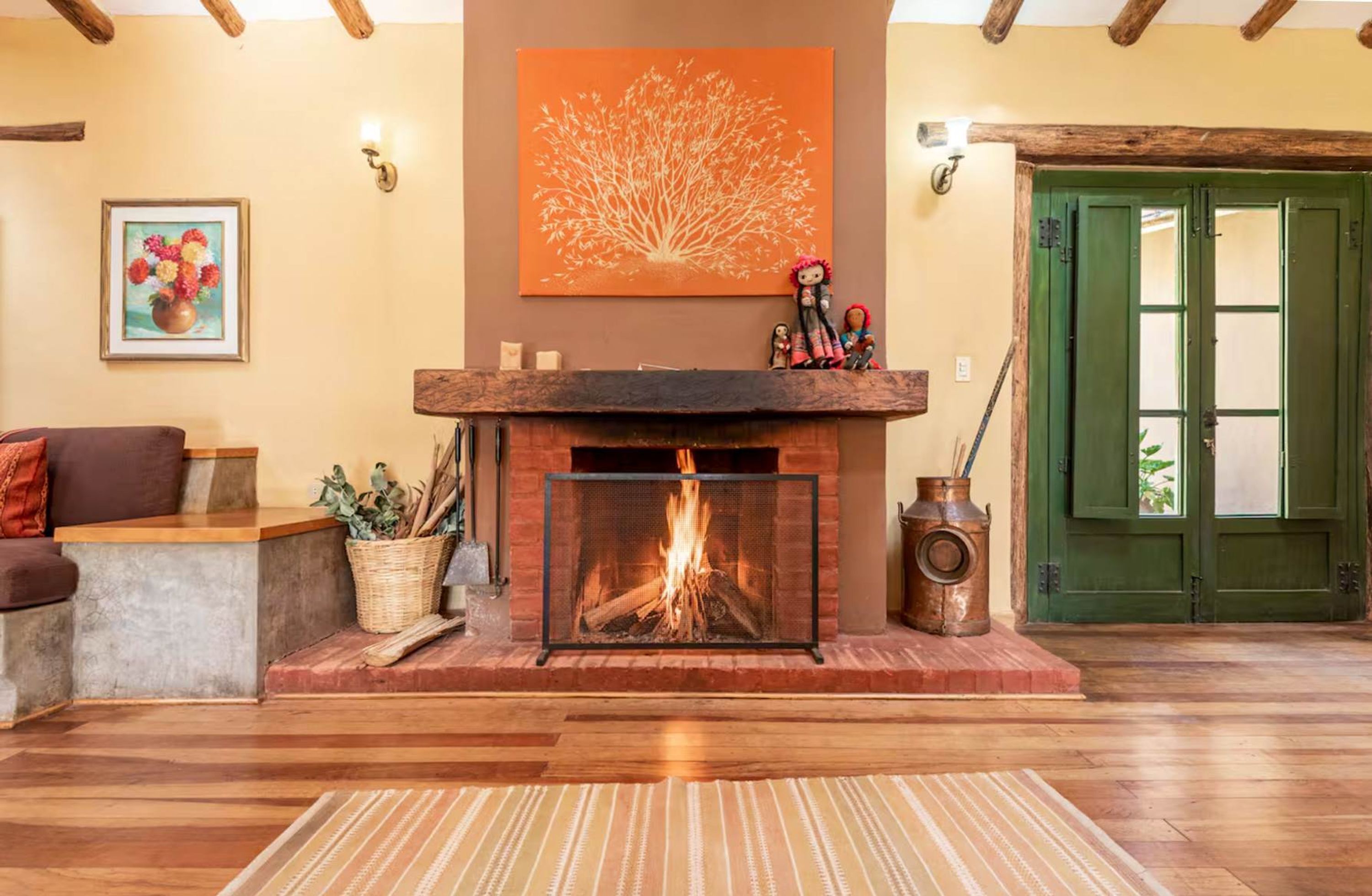 Un salon chaleureux avec une cheminée, une porte verte et un tableau représentant un arbre.