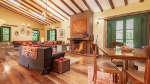 A spacious living room with a fireplace, wooden beams, and a dining area with a table and chairs. - w Peaceful 4BR Villa With Nature View (Pisac)