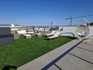 A rooftop terrace with artificial grass, lounge chairs, and a hanging chair. - Residencial Breeze 1A by Bookaparadise (Finestrat)