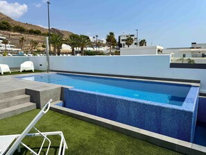 A rectangular swimming pool with blue tiles, surrounded by artificial grass and white lounge chairs. - Resort Seascape Villa 8 by Bookaparadise (Finestrat)