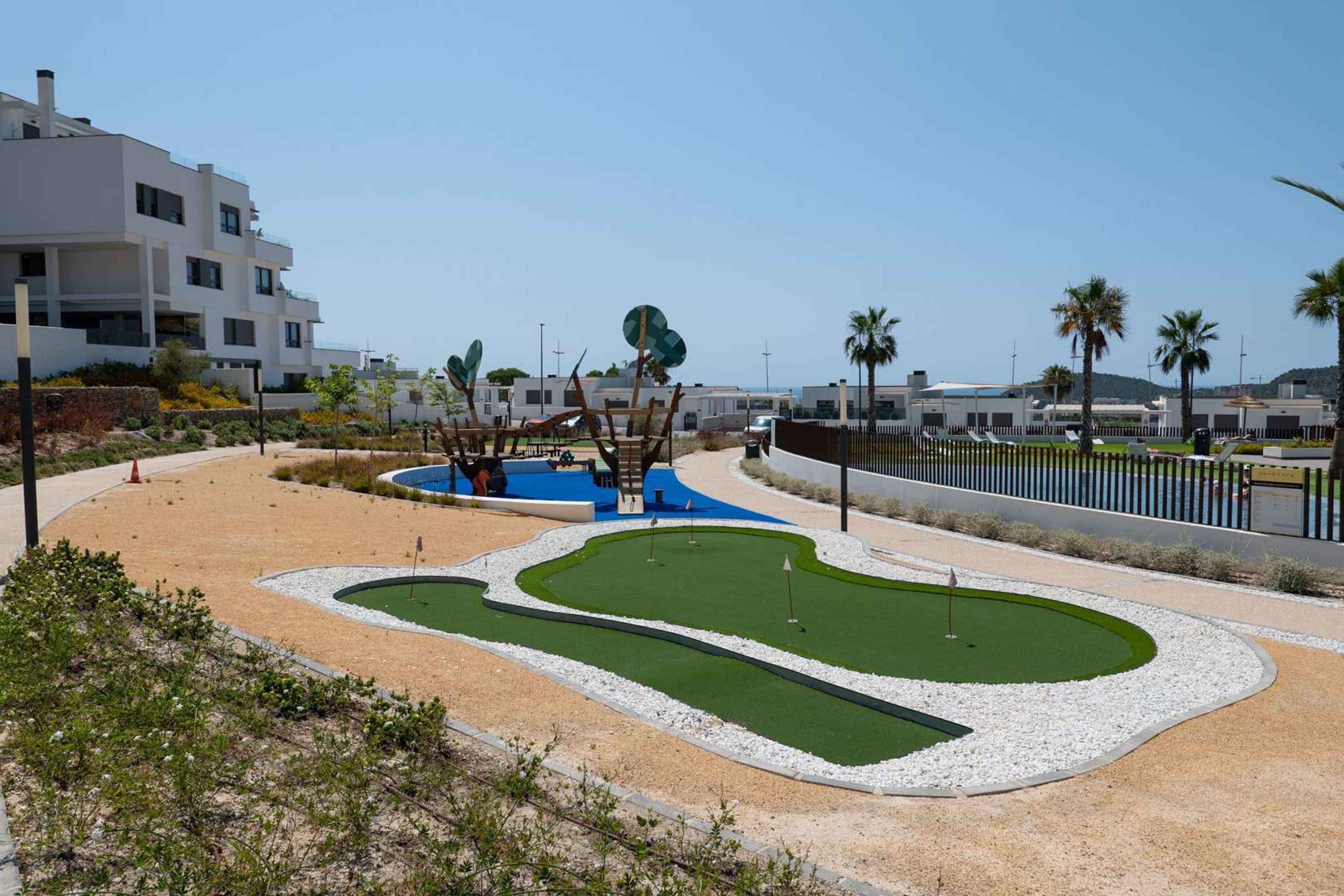 A golf course with a putting green, sand bunkers, and a water hazard.
