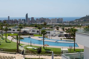 Un resort con piscina, palmeras y vistas del horizonte urbano.