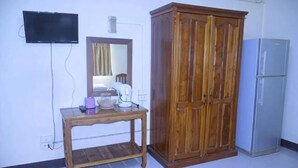 A room with a wooden cabinet, a table with a mirror, a television mounted on the wall, and a refrigerator. - Peamsuk Sweet Prachin Buri (Prachinburi)