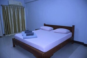 Ein Einzelbett mit Holzrahmen, einer weißen Matratze und zwei Kissen.