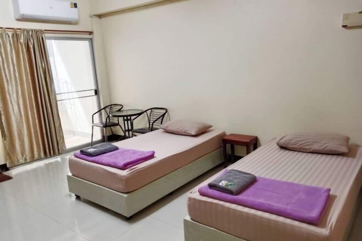 Una habitación con dos camas, una mesita y una silla.
