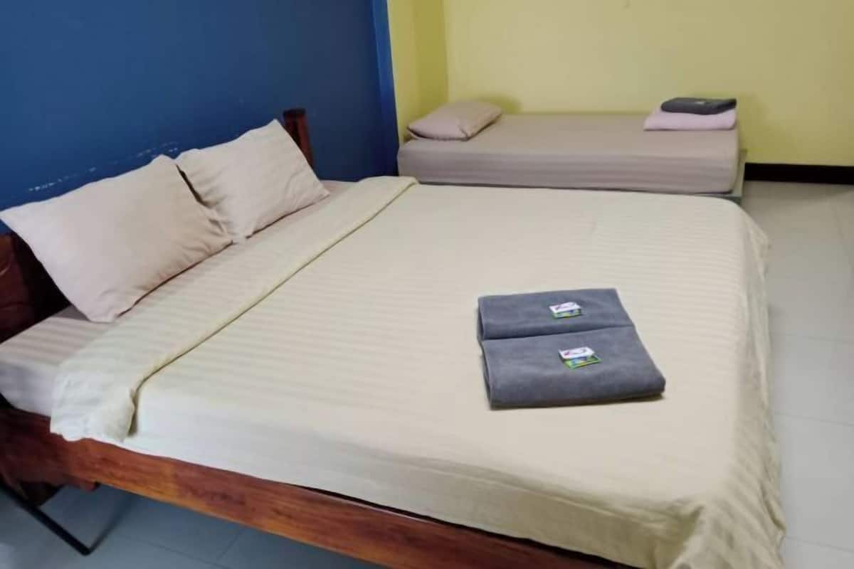 Una habitación con una cama de madera, una cama más pequeña y una pared azul.