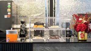 A breakfast bar with a coffee machine, a fruit dispenser, and a vase with red flowers. - ZJ House(Phuket Town) (Phuket)