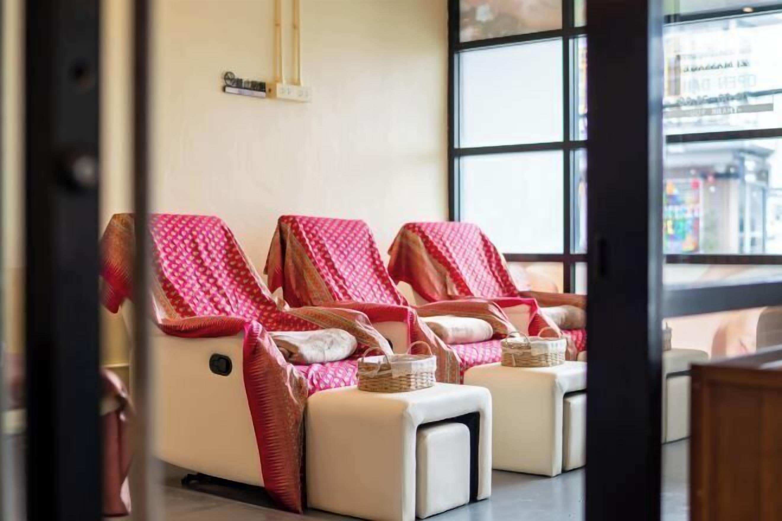 A spa room with three massage chairs, each with a red towel and a small basket.