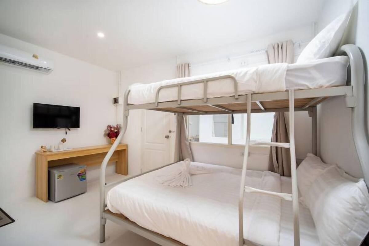 Habitación con literas, televisión, un escritorio pequeño y un refrigerador.