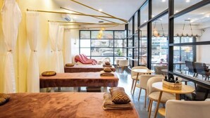 A modern spa area with massage tables, chairs, and a view of the city through large windows. - ZJ House(Phuket Town) (Phuket)