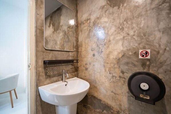 A bathroom with a white sink, a mirror, a towel rack, and a no-smoking sign. - ZJ House(Phuket Town) (Phuket)