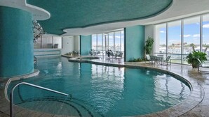 An indoor swimming pool with a curved ceiling, large windows, and a view of the city. - NEW! 3.5 bedroom 3.5 bath condo in Orange Beach, walking distance to Flora-Bama! (Orange Beach)