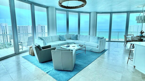 A modern living room with a large sofa, a coffee table, and a view of the ocean. - NEW! 3.5 bedroom 3.5 bath condo in Orange Beach, walking distance to Flora-Bama! (Orange Beach)
