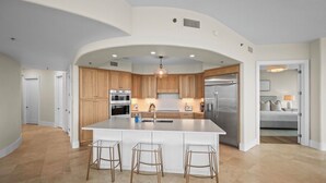 A modern kitchen with a large island, wooden cabinets, stainless steel appliances, and a curved ceiling. - NEW! 3.5 bedroom 3.5 bath condo in Orange Beach, walking distance to Flora-Bama! (Orange Beach)