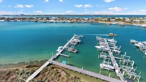 A marina with boats docked, a pier, and a coastal town in the background. - NEW! 3.5 bedroom 3.5 bath condo in Orange Beach, walking distance to Flora-Bama! (Orange Beach)