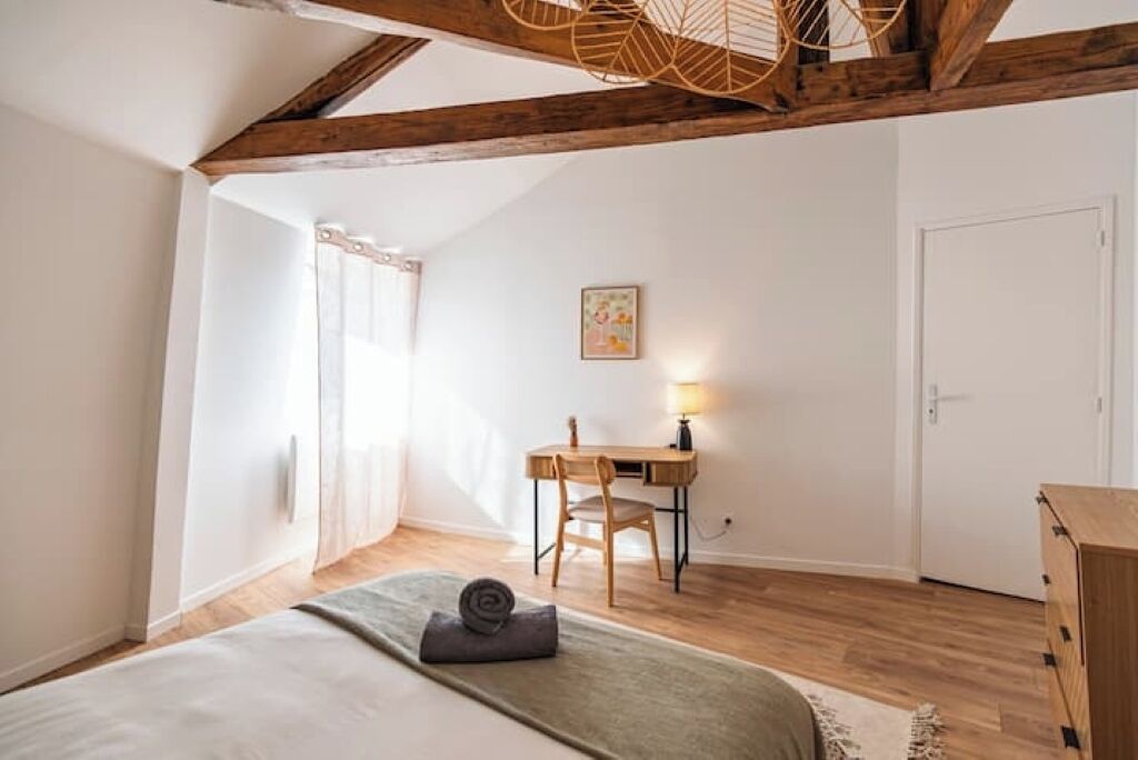 A bedroom with a bed, a desk, and a chair.