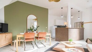 Ein modernes Wohnzimmer mit Essbereich, einer Küche und einem großen Spiegel.