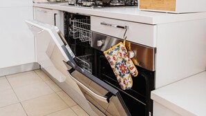 A kitchen with a dishwasher, oven, and a wooden cabinet.
