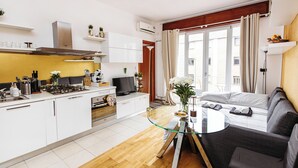 A modern kitchen with white cabinets, a gas stove, and a dining area with a glass table.