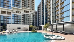 Un edifici residencial modern amb piscina, gandules i una petita zona de jardí.