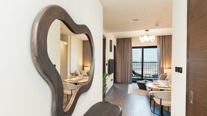 Habitació d'hotel moderna amb un gran mirall, zona de menjador amb taula rodona i cadires, i un balcó amb vistes.