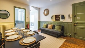 A dining area with a table set for six, a sofa, and a door to the right.