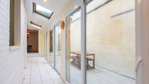 A corridor with a skylight, sliding glass doors, and a view of an outdoor patio area.