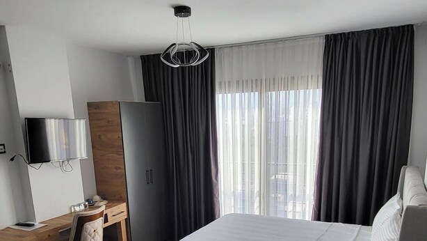 Ein Hotelzimmer mit zwei Betten, einem Schreibtisch mit Stuhl, einem Fernseher und einem Kleiderschrank.