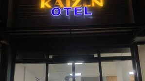 Das Außere des Hotels Kaizun mit Glastür und Pflanzen in Töpfen.