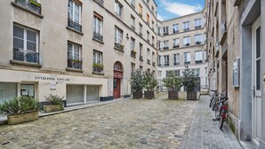 A courtyard with cobblestone pavement, a building with a sign reading "ENTREPRISE EDOUARD," and bicycles parked along the side. - Duplex Center of Paris (Paris)