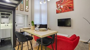 A modern dining area with a wooden table, black chairs, and a red sofa. A flat-screen TV is mounted on the wall above the table. - Duplex Center of Paris (Paris)