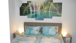 A bed with patterned bedding, two bedside tables with lamps, and a wall with a nature-themed artwork. - Apartment 'Carpe Diem' with Shared Terrace, Shared Garden and Wi-Fi (Rust)