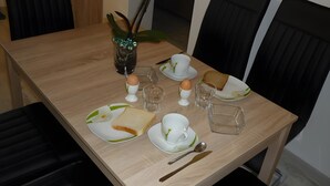 A dining table with plates, cups, a spoon, and a vase with flowers. - Apartment 'Carpe Diem' with Shared Terrace, Shared Garden and Wi-Fi (Rust)